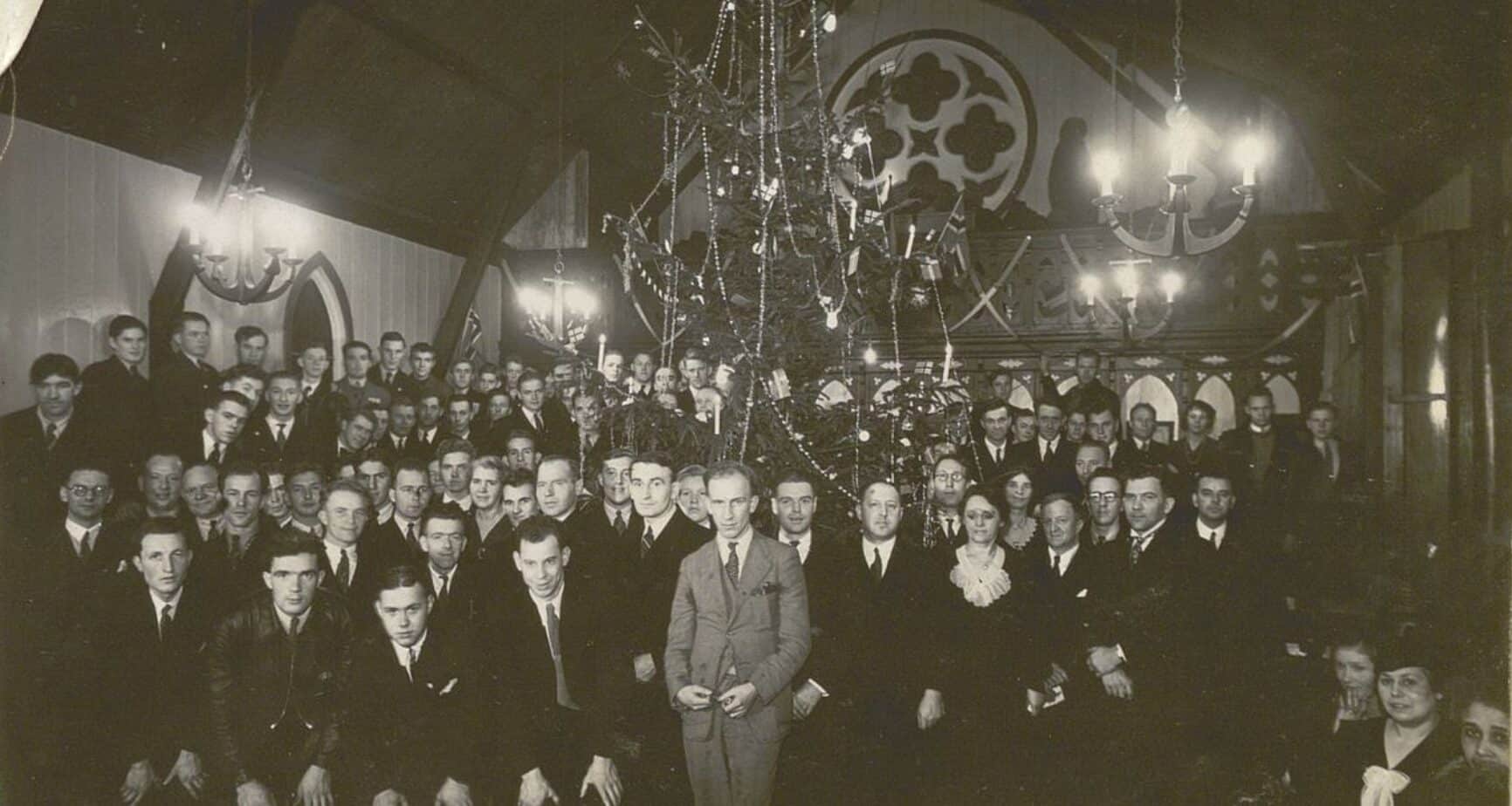 Gruppebilde fra en juletrefest i 1937. Et pyntet tre står midt i rommet, omgitt av festkledde deltakere.