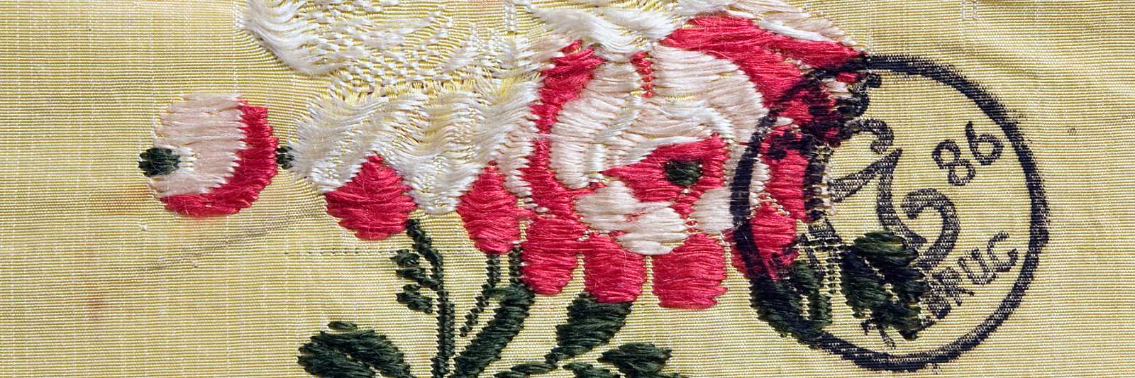 Detalj av dåpsløyert fra gården Vaker i Norderhov på Ringerike. Stoffet, som er av silke, var vevd i Spitalfields nær London på 1770-tallet. Eieren hadde sørget for å få det stemplet slik myndighetene hadde bestemt. Stemplet lød: ”C7 (under krone) 1786 TIL BRUG”. (En løyert var et poseliknende klesplagg til spedbarn.)