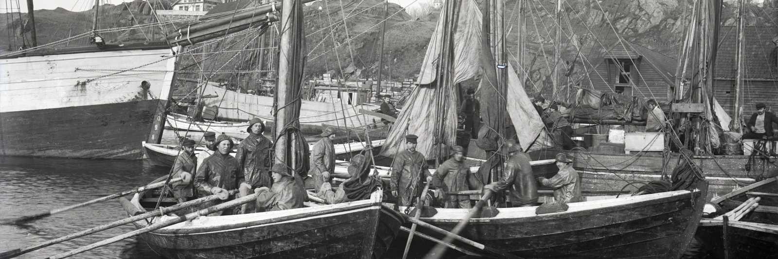 Utsnitt som viser fiskebåter ved Havnaberg i Haugesund. Tårnet på Skåre kirke kan skimtes mellom mastene på originalbildet