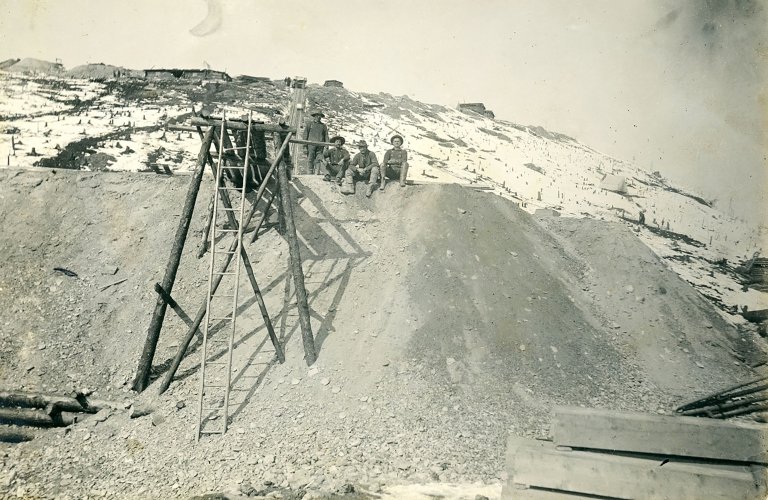 Gravel and sand piled up during winter, ready for washing. Photographer: Asahel Curtis.
Behind the men, you can see French Gulch and a cleared area. Martin sits far right; Daniel far left
