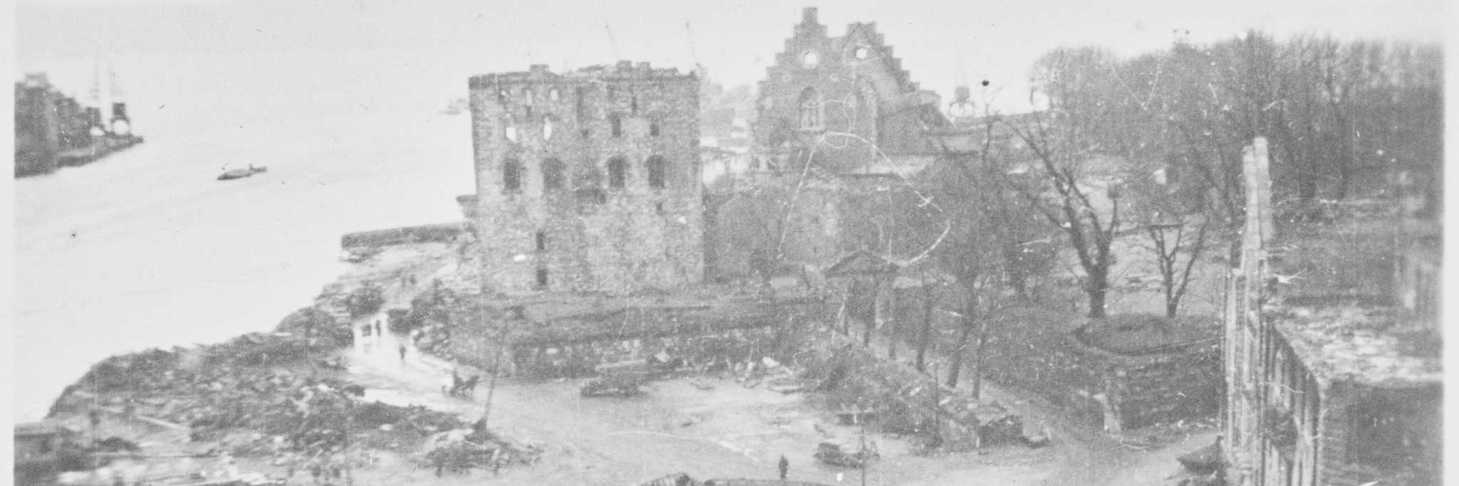ETTER EKSPLOSJONEN: Foruten flere båter slengt langt opp på land er det ufattelig hvor store skader Rosenkrantztårnet og Håkonshallen hadde etter eksplosjonsulykken i Bergen 20. april 1944. FOTO UKJENT UTLÅN: NTBS KRIGSARKIV/ARKIVVERKET