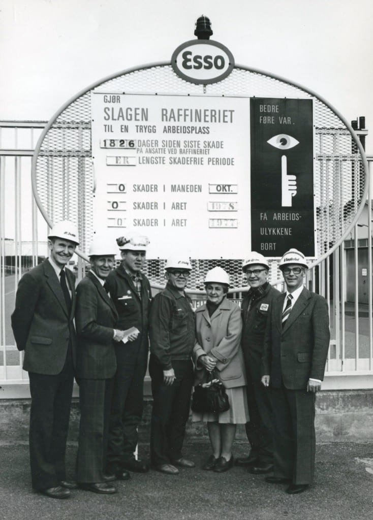 Sikkerhetsskiltet ved hovedinngangen til raffineriet i 1978. Fra venstre: Raffineridirektør Øystein Dahle, Tor Arnevåg fra Vern og Velferd, Svein Nilsen, Charles Haug, Anna Gustavsen fra Statens Arbeidstilsyn, Gunnar Steen Larsen og Kjell Naglestad. Fotograf ukjent.