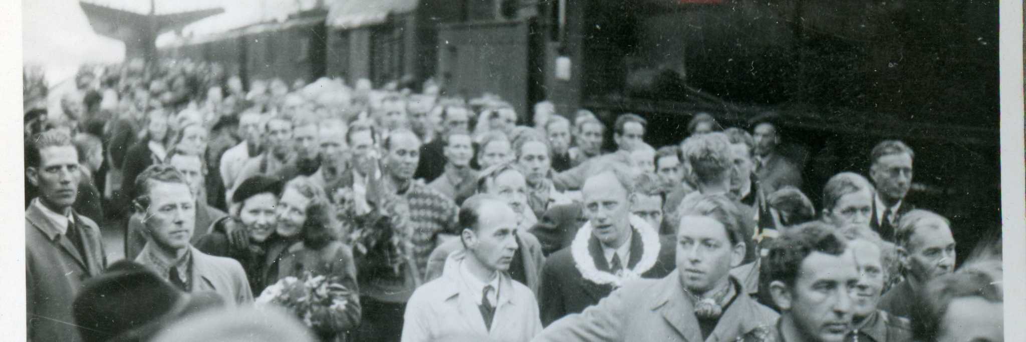 "Tysklandsfanger kommer" (original bildetekst). Foto fra album etter Leon Jacobsen. Den 28. mai 1945 skrev Bergens Tidende dette om begivenheten som fant sted samme dag: "Den lykkeligste dag i vårt liv... Studenter, brannmenn, Telavågfolk og andre fanger hjem fra Tyskland i dag. En gripende mottagelse ved jernbanestasjonen hvor tusener av mennesker var samlet".