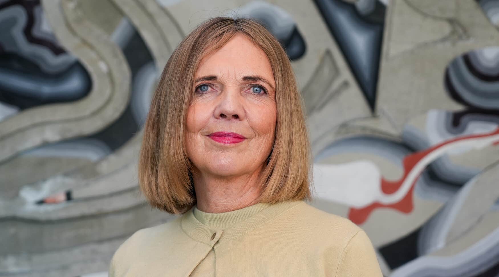 Kvinne foran betongvegg med abstrakt kunst.