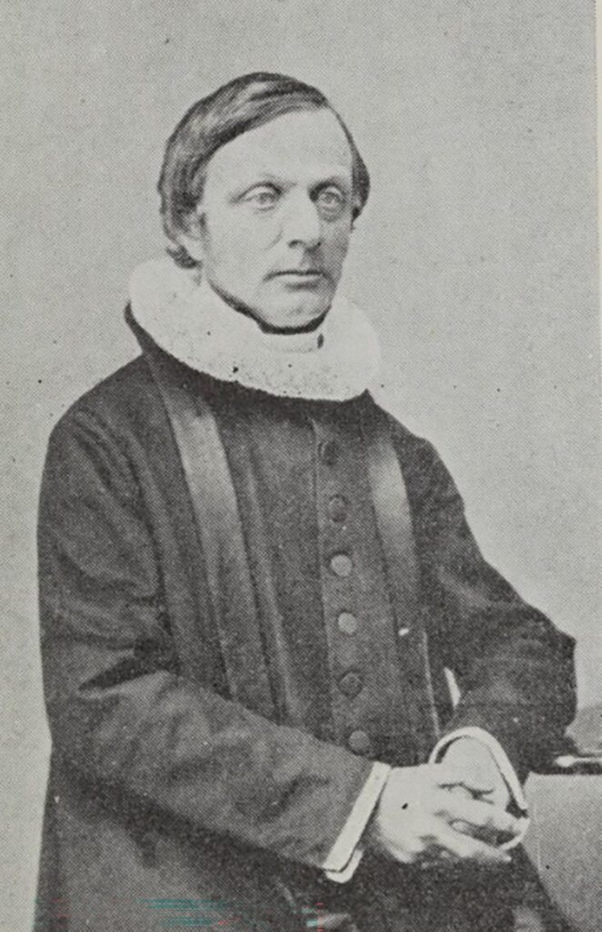 Sort‑hvitt portrett av Gedde i prestekjole og pipekrage, hentet fra boken «Træk av Hetlands historie 1814–1914».