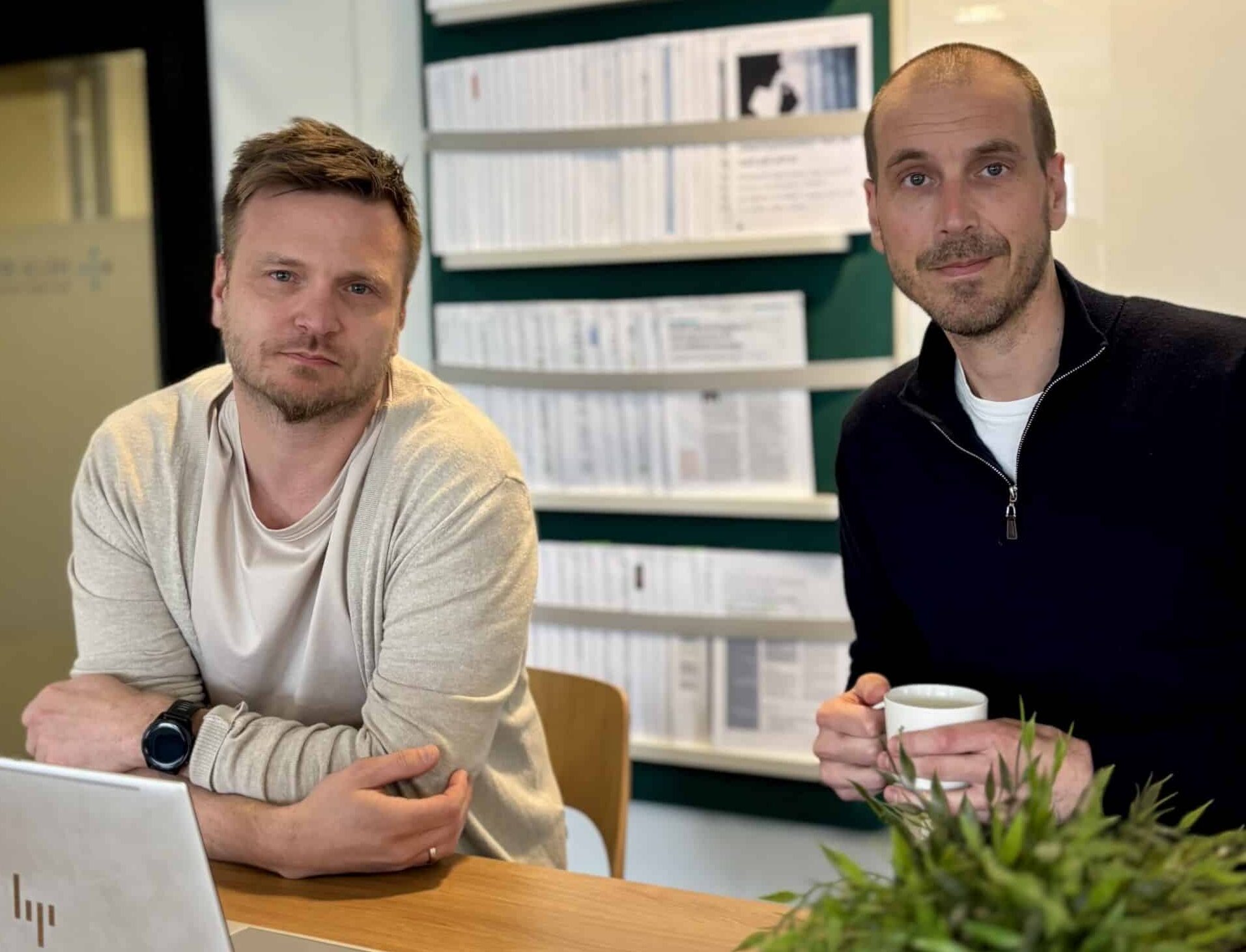 Foto av to menn som sitter på et kontor. De har en pc foran seg.