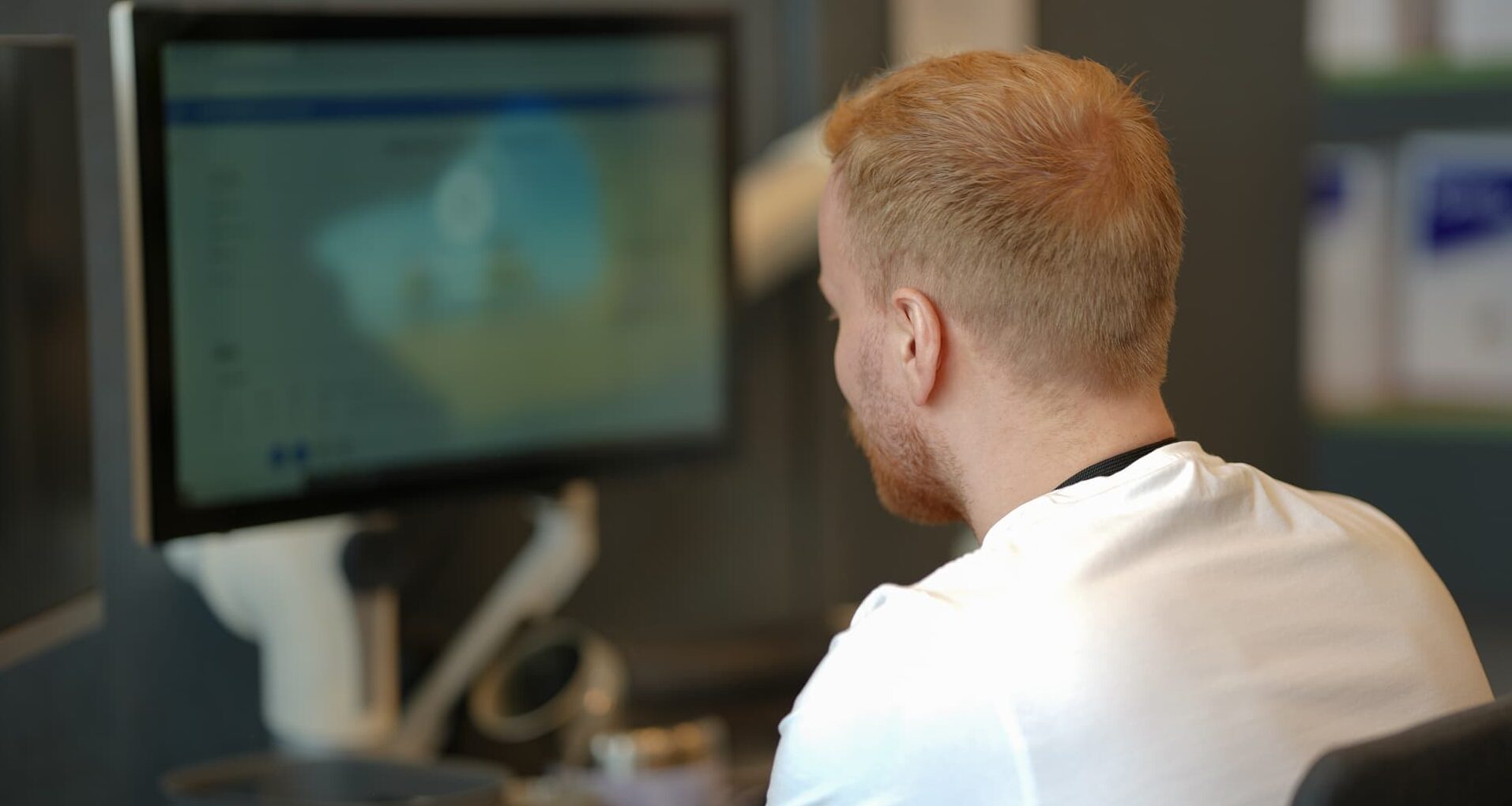 Mann jobber ved datapult, ser på skjerm som viser abstrakt bilde.
